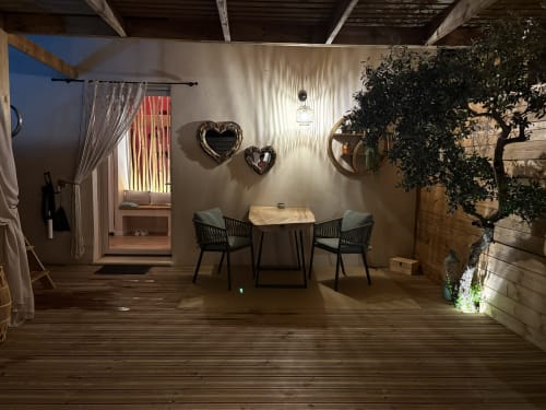 Élégante salle à manger extérieure à Suite l'Olive Sacrée à Cabannes avec chaises bistrot, miroirs cœur et plantes luxuriantes