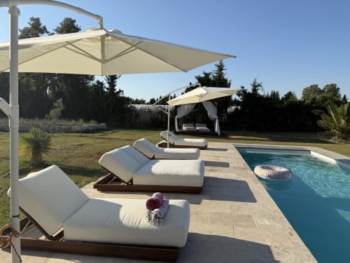 Lounge luxe en bord de piscine au Domaine Mas Lafleur avec transats, parasols cantilever et daybed couvert à Châteaurenard