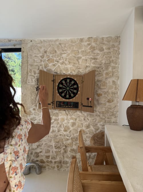 Un client joue aux fléchettes électroniques dans la salle de jeux aux murs en pierre du Domaine Mas Lafleur, Châteaurenard