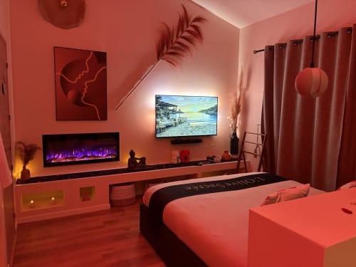 Suite hôtelière moderne à Cabannes avec murs corail, cheminée, TV et literie luxueuse