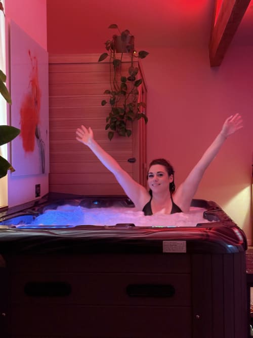 Femme se relaxant dans un bain à remous aux néons roses à l'hôtel Suite & Duplex de Cabannes