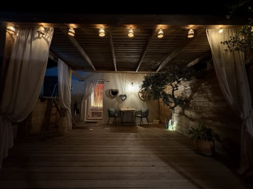 Élégante terrasse nocturne de l'hôtel Suite & Duplex à Cabannes, avec pergola, guirlandes lumineuses, coin salon et végétation luxuriante