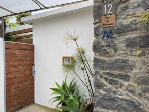 Entrance to Casa da Bordadeira at BHF Residences with wooden door, stone wall, and tropical plants in Arco da Calheta,
