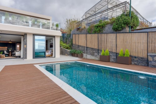 Villa de Luxo BHF Residences em Arco da Calheta com piscina turquesa, deck de madeira e casa moderna de vidro