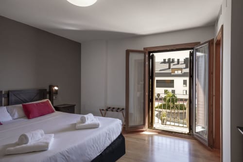 Bright double bedroom at Casa Azcona with balcony overlooking Zizur Mayor, featuring modern furnishings and mountain views