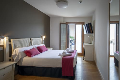 Chambre double moderne à l'hôtel Casa Azcona à Zizur Mayor avec vue sur les montagnes, lit blanc et accents bordeaux