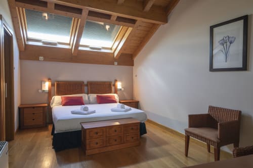 Bright double bedroom at Casa Azcona with wooden beams, skylight windows, mountain views, and modern furnishings in Zizur
