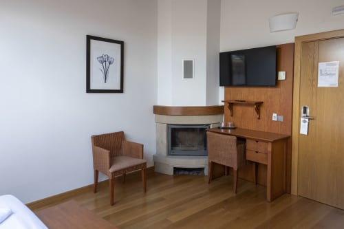 Modern hotel room at Casa Azcona with fireplace, wooden desk, armchairs, TV, and wooden furnishings