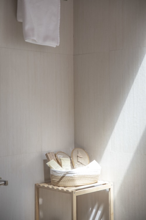 Minimalist bathroom corner at Casa Azcona with woven basket, toiletries, and white towel under natural light