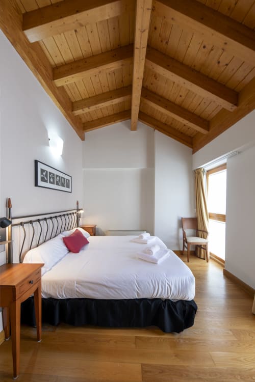 Spacieuse chambre twin à Casa Azcona avec poutres en bois apparent, draps blancs et vue sur les montagnes à Zizur Mayor