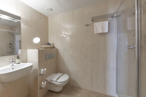 Salle de bain moderne à l'hôtel Casa Azcona avec toilettes murales, lavabo blanc, douche vitrée et sèche-serviettes électrique