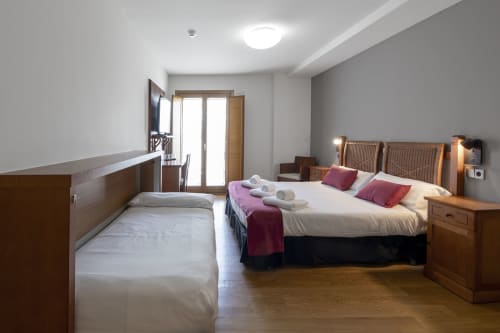 Chambre Triple Familiale lumineuse à Casa Azcona avec deux lits, mobilier en bois et balcon vue sur les montagnes à Zizur Mayor