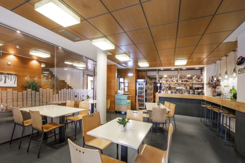 Bar et salle à manger de l'hôtel Casa Azcona à Zizur Mayor avec plafond en bois, tables blanches et sièges modernes