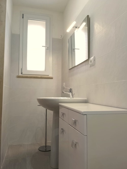 Bagno moderno presso Il Corso Guest House a Veglie con vanità bianca, lavabo su piedistallo, specchio illuminato e finestra