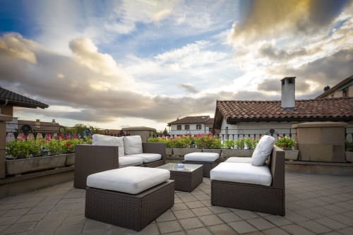 Terrasse sur le toit de l'hôtel Casa Azcona à Zizur Mayor avec sièges de détente, jardinières fleuries et ciel au coucher du soleil