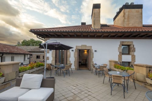 Terrasse de la Casa Azcona à Zizur Mayor avec mobilier, parasol et architecture en pierre