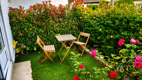 Terrasse de jardin accueillante à la villa Maison Ô de Caps à Sangatte avec chaises en bois, table, roses roses et vue sur les haies