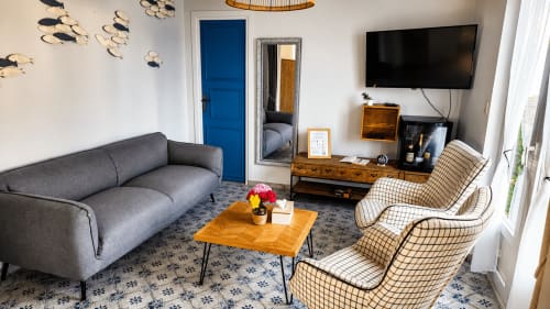 Séjour moderne de la villa Ô de Mer à Sangatte : canapé gris, fauteuils à motifs, table en bois et télévision écran plat