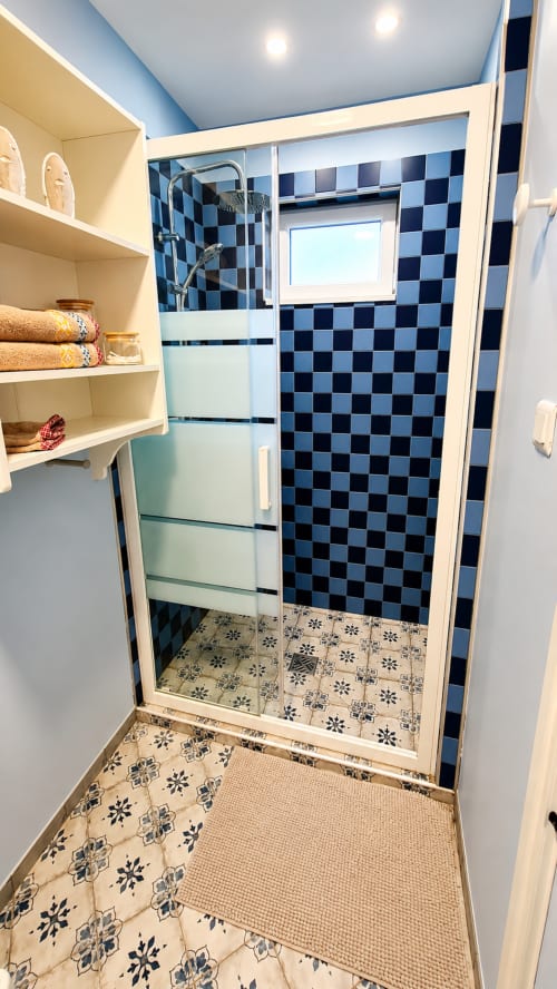 Salle de bain moderne avec carrelage bleu à carreaux, douche à l'italienne, rangements et carreaux de sol décoratifs à la villa Ô de Mer