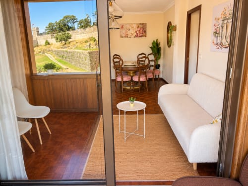 Apartamento hotel Holibai en Baiona con sofá crema, comedor y vistas al castillo
