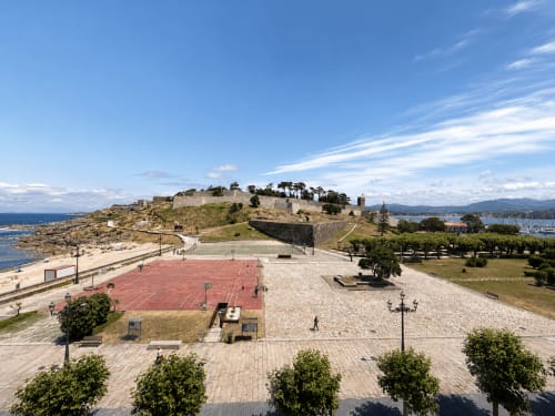 Instalaciones del hotel Holibai en Baiona con cancha deportiva, playa, colina fortificada y vistas costeras