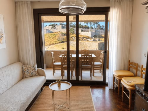 Habitación del hotel Holibai en Baiona con balcón con vistas a las murallas del castillo medieval y zona de estar amueblada