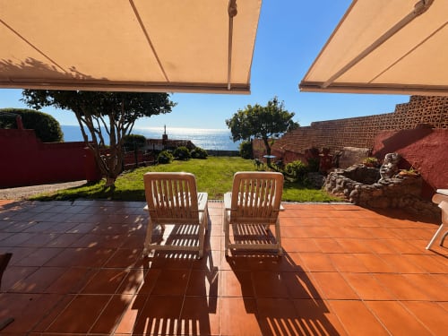 Terraza con tumbonas bajo toldos retráctiles, vistas al mar, cabaña Oia con jardín y paisaje costero