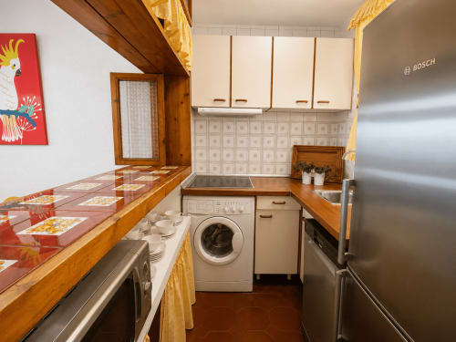 Cocina compacta en apartamento Batea de Holibai, Baiona, con muebles de madera, electrodomésticos modernos y acceso a vistas al mar