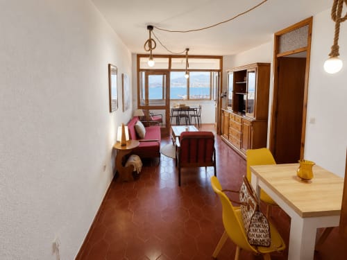 Apartamento Batea en Baiona con vistas al mar, muebles de madera, sillas amarillas y ventanales con vistas a la costa