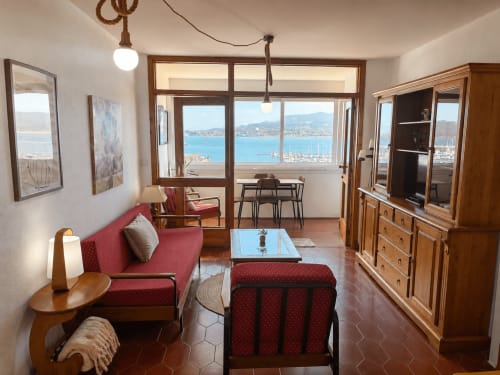 Apartamento clásico Batea en Holibai Baiona con vistas al mar, sofá rojo, muebles de madera y vistas completas de la bahía