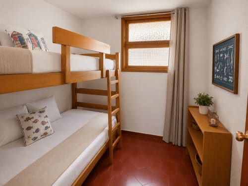 Acogedora habitación con literas de madera, vistas al mar y suelo de baldosas rojas en el hotel Holibai de Baiona