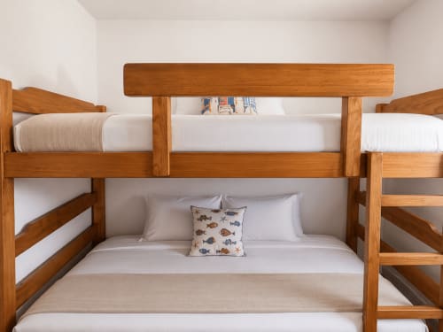 Literas de madera con ropa de cama blanca y almohada estampada con peces en el apartamento Holibai, Baiona