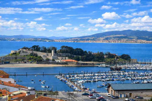 Marina de Baiona con castillo histórico, veleros y vistas de la bahía desde el apartamento Holibai
