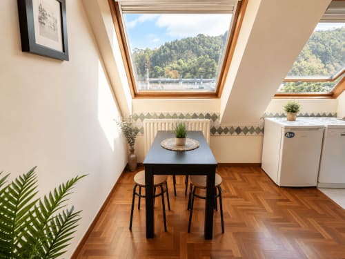 Luminoso loft en Baiona con claraboya, mesa de comedor negra, suelos de madera, plantas y vistas al bosque
