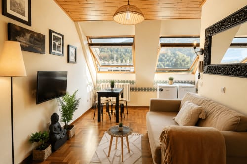 Acogedor apartamento en buhardilla de Baiona con techo de madera, sofá, TV, comedor y vistas a las montañas