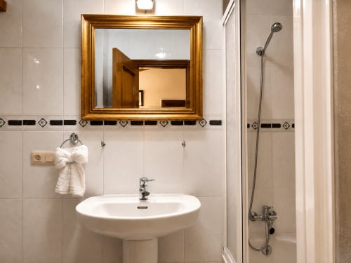 Baño moderno en apartamento Holibai, Baiona con lavabo pedestal blanco, espejo marco dorado y ducha