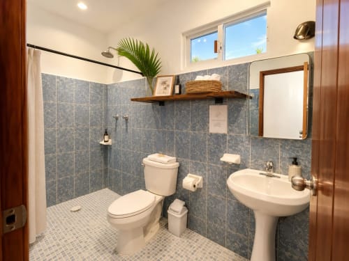 Baño moderno en Hotel Isla Mujeres Centro con ducha abierta, lavamanos pedestal y decoración tropical