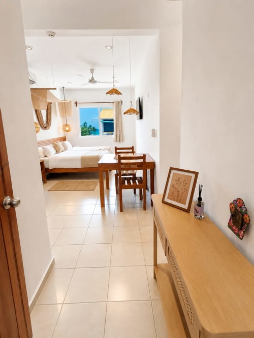 Habitación moderna del Hotel Isla Mujeres Centro con cama de madera, lámparas colgantes, vista al océano y mobiliario contemporáneo