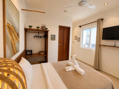 Suite moderna del Hotel Isla Mujeres Centro con cama queen, TV de pantalla plana, detalles de madera y vista al océano