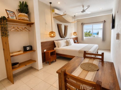 Suite moderna y luminosa en Hotel Isla Mujeres Centro con cama de madera, comedor, vista al océano y decoración tropical