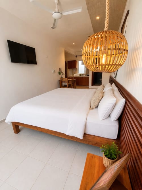 Suite moderna en Isla Mujeres Centro con cama de madera, lámpara colgante tejida, TV y kitchenette en Isla Mujeres, México