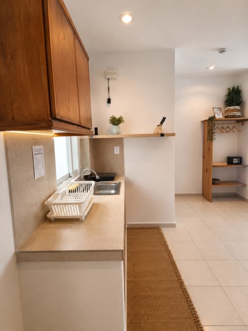 Cocina moderna en Suite 9 del Hotel Isla Mujeres Centro con fregadero de acero inoxidable, gabinetes blancos, estantería de madera y