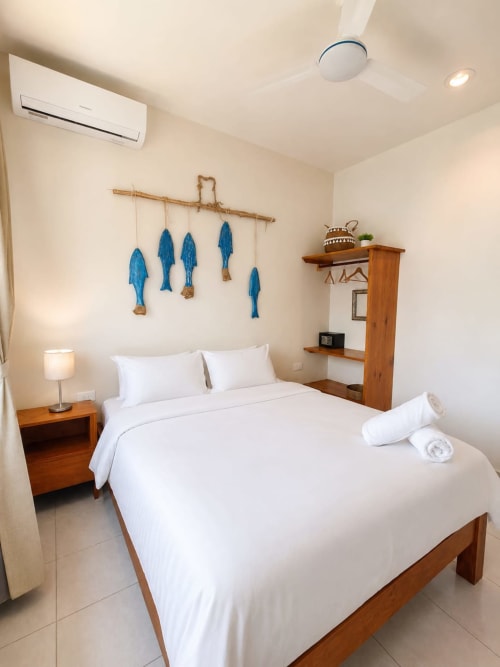Habitación moderna del Hotel Isla Mujeres Centro con cama de madera, ropa de cama blanca, decoración azul de peces y muebles de madera