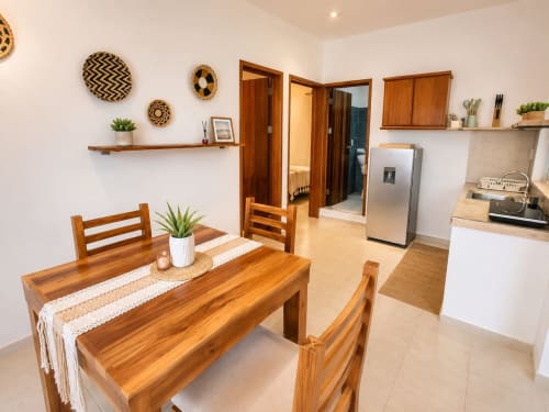 Zona de comedor Suite 13 con mesa de madera, cocina y electrodomésticos de acero inoxidable en Hotel Isla Mujeres Centro