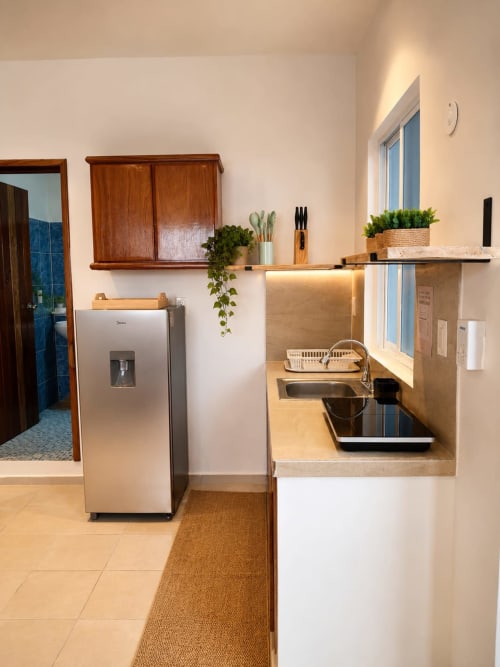 Cocina moderna en Suite 13 del Hotel Isla Mujeres Centro con electrodomésticos de acero inoxidable, estantería de madera y vistas al océano