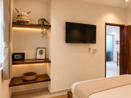 Habitación moderna en Isla Mujeres Centro con TV de pantalla plana, repisas de madera, plantas en maceta y vistas al océano desde la suite.