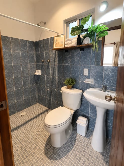 Baño moderno con ducha abierta, lavamanos pedestal blanco e inodoro en Suite 14 del Hotel Isla Mujeres Centro con vista al mar