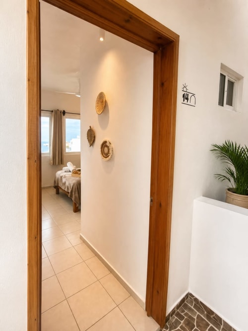 Entrada Suite 14 en Hotel Isla Mujeres Centro con pasillo de azulejos, marco de madera y dormitorio con vista al mar
