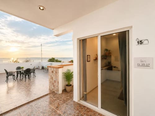 Terraza de la Suite 15 en Hotel Isla Mujeres con vistas al océano, área de estar y puertas de cristal al dormitorio