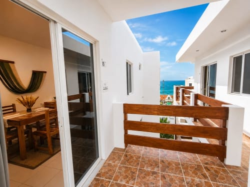 Terraza de la Suite 15 con vistas al océano, barandal de madera, zona de comedor y Mar Caribeño en Hotel Isla Mujeres Centro
